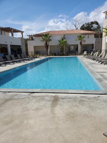 une grande piscine avec des chaises et un bâtiment dans l'établissement Residence Marina di Bravone, à Linguizzetta