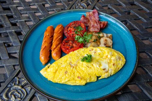 a blue plate with an omelet and sausage and vegetables at Phongsavath Boutique Hotel in Vientiane