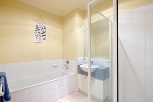 a bathroom with a bath tub and a sink at Beachfront Bliss - shared indoor pool & spa in Cowes