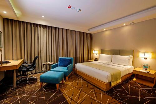 a hotel room with a bed and a blue chair at Holiday Inn Chennai OMR IT Expressway by IHG in Chennai