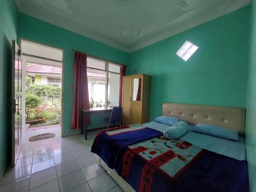 een slaapkamer met een bed met groene muren en een raam bij Grand Syariah Guest House Humanitas in Pematangsiantar