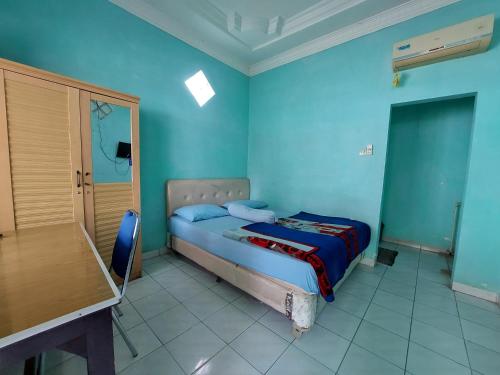 a blue bedroom with a bed and a table at Grand Syariah Guest House Humanitas in Pematangsiantar