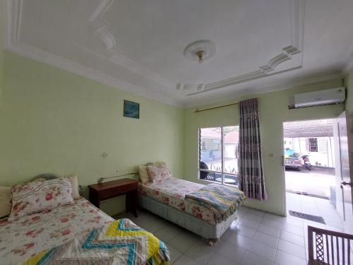 a bedroom with two beds and a window at Grand Syariah Guest House Humanitas in Pematangsiantar