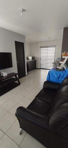 a living room with a black couch and a television at Casa en fraccionamiento privado in Apodaca