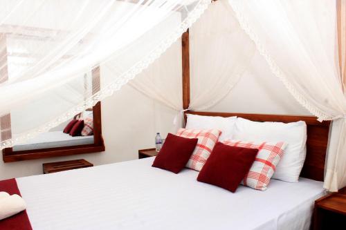 a bedroom with a bed with red and white pillows at Green Hut Nature Resort in Sigiriya