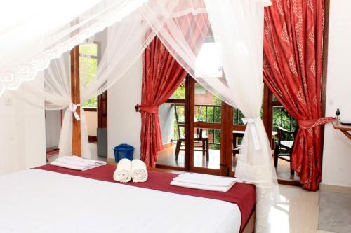 a bedroom with a bed with red and white curtains at Green Hut Hotel & Restaurant with Unique View Point in Sigiriya
