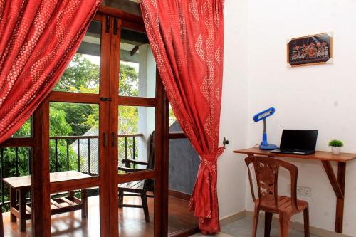 a room with a door and a desk with a laptop at Green Hut Nature Resort in Sigiriya