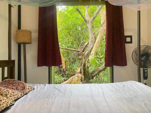 ein Schlafzimmer mit einem Bett und einem Fenster mit einem Baum in der Unterkunft Maina Home's Gₐₗₗₑ in Bope