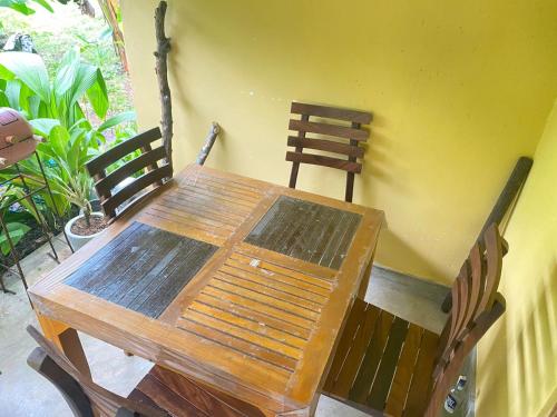 einem Holztisch und Stühlen neben einer gelben Wand in der Unterkunft Maina Home's Gₐₗₗₑ in Bope