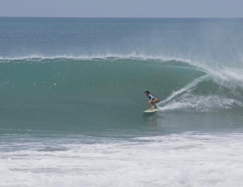 una persona montando una ola en una tabla de surf en el océano en Posada Mexico, en Zipolite