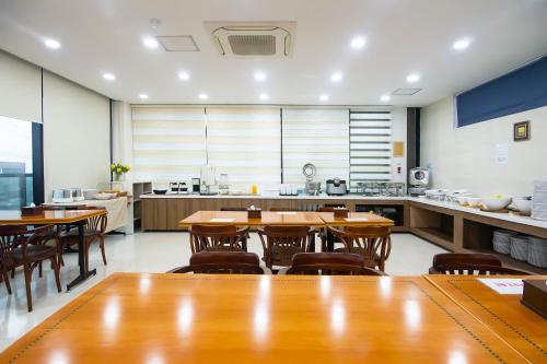 a large kitchen with wooden tables and chairs at Sims Hotel in Jeju
