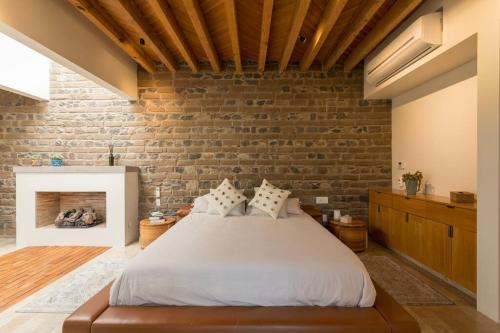 a bedroom with a bed and a brick wall at Jacaranda House in San Miguel de Allende