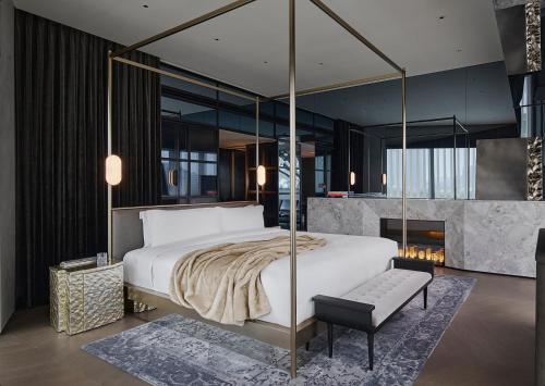 Kimpton Qiantan Shanghai, an IHG Hotel في شانغهاي: غرفة نوم بسرير كبير ومدفأة