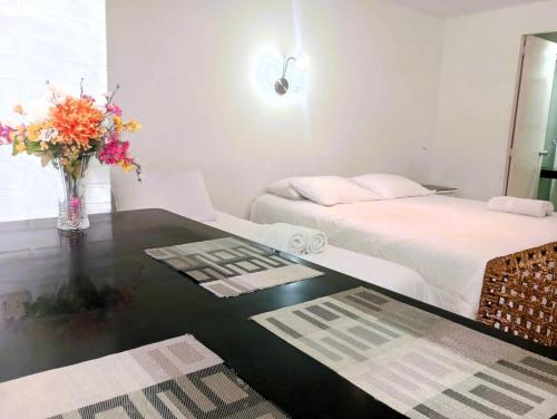 a bedroom with a bed and a table with a vase of flowers at Monterrico Suites Hotel in Lima