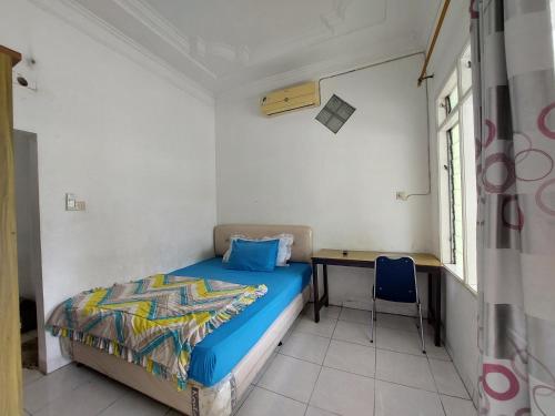 a small bedroom with a bed and a desk at Grand Syariah Guest House Humanitas in Pematangsiantar