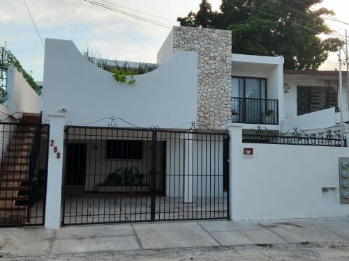 a white house with a gate with a large letter t at Modern loft with AC near Paseo Montejo - El Rosal in Mérida