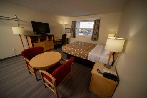 a hotel room with a bed and a table and chairs at Northern Lights Inn in Fort Saint John