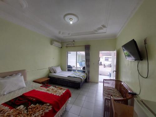 a room with two beds and a television in it at Grand Syariah Guest House Humanitas in Pematangsiantar