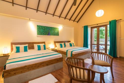 a bedroom with two beds and a table and chairs at Yala Chalets by Lalan Leisure in Kirinda