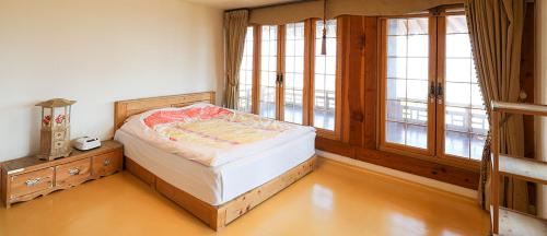 ein Schlafzimmer mit einem Bett in einem Zimmer mit Fenstern in der Unterkunft Korea Traditional Hotel O Dong Jae in Yeosu