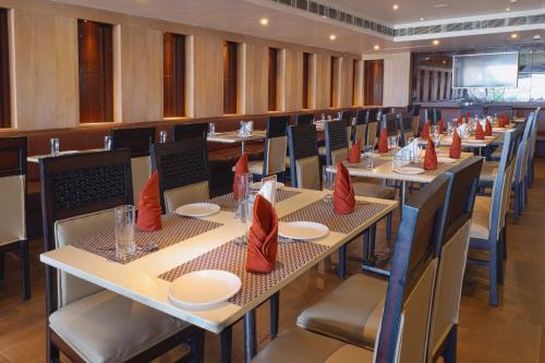 un comedor con mesas y sillas con servilletas rojas en Hotel Prism Jorhat, en Jorhāt