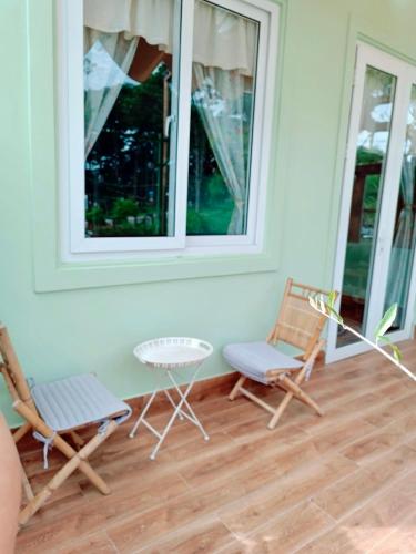 a porch with two chairs and a table and two windows at Whispering Pines Dalat (Thông Thì Thầm ĐL) in Da Lat