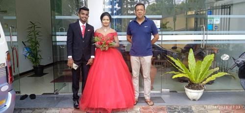 a woman in a red dress standing next to two men at Vino Villa Tourists & Local Accommodations - 24 Hrs in Kandy