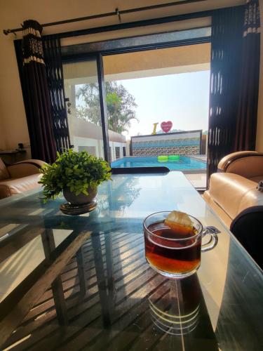 un drink su un tavolo di vetro in una stanza con piscina di THE PERFECT STAYS: CHOUDHARY VILLA a Lonavala