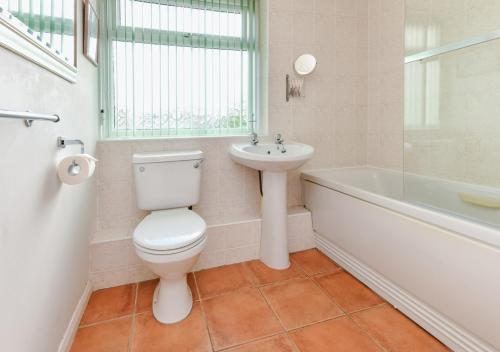 a bathroom with a toilet and a sink and a tub at 139 Cae Du in Abersoch