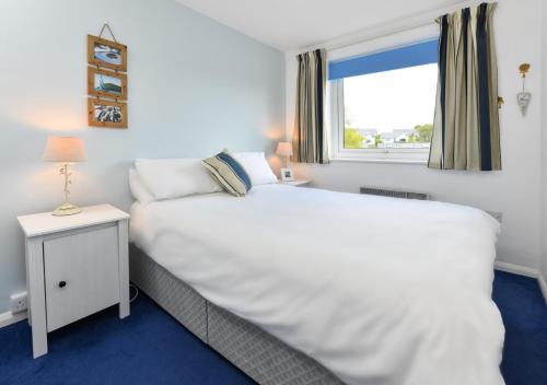 a bedroom with a large white bed and a window at 139 Cae Du in Abersoch