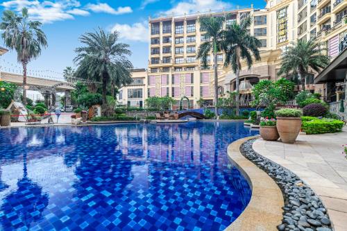 een zwembad in een stad met palmbomen en gebouwen bij Legend International Hotel in Huizhou