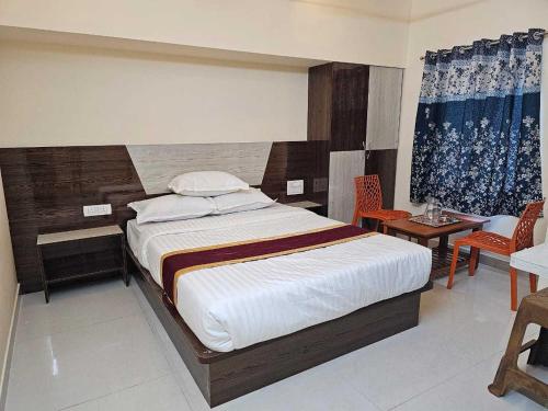 een slaapkamer met een bed en een tafel en stoelen bij Collection O Petals Otium in Pālasmudram