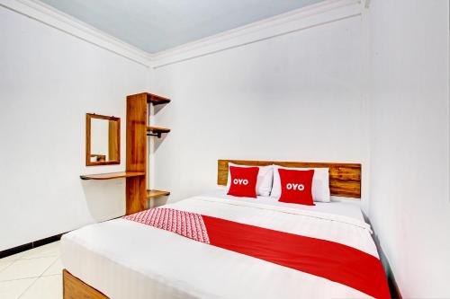 Schlafzimmer mit einem weißen Bett und roten Kissen in der Unterkunft OYO 93253 Guest House Arundaya Syariah in Purwokerto