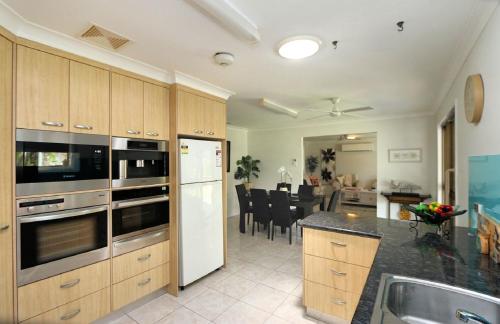 a kitchen with stainless steel appliances and a dining room at 4 Jacques Court in Bargara