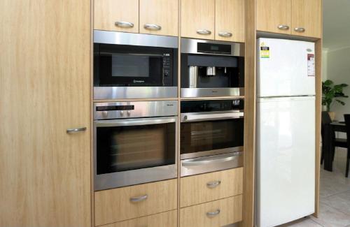 a kitchen with three ovens and a refrigerator at 4 Jacques Court in Bargara