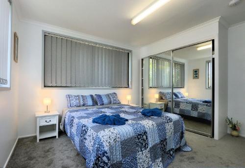 a bedroom with a bed with blue sheets and a mirror at 4 Jacques Court in Bargara
