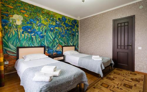 Dos camas en una habitación con un cuadro en la pared. en Арт-отель ololoFamily, en Chon-Sary-Oy