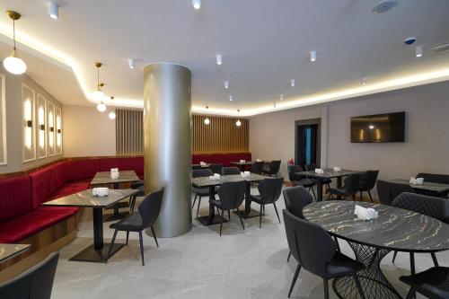 un restaurante con mesas y sillas y un sofá rojo en Ugurlu Hotel, en Gaziantep