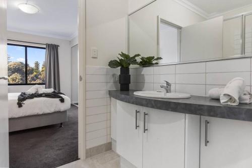 a white bathroom with a sink and a mirror at Luxury Retreat in the Heart of Subiaco in Perth