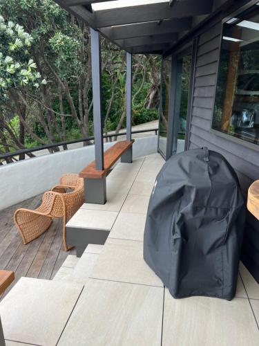 a covered porch with a bench and a table at Reefers in Kuaotunu