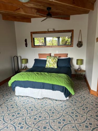 a bedroom with a green bed with two lamps at Reefers in Kuaotunu