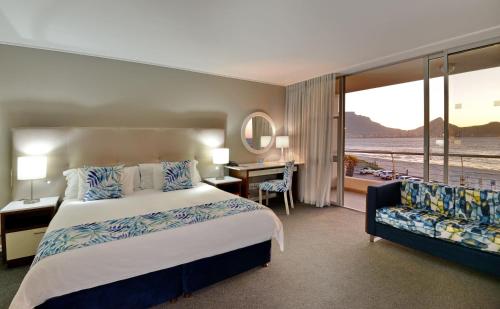 a hotel room with a bed and a desk and a window at Lagoon Beach Hotel & Spa in Cape Town