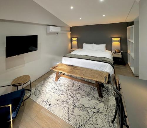 Ferns Country Lodge في مافكينج: غرفة نوم بسرير وطاولة وتلفزيون