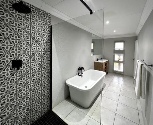 a bathroom with a white tub and a glass wall at Ferns Country Lodge in Mahikeng