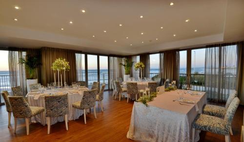 a banquet room with tables and chairs and windows at Lagoon Beach Hotel & Spa in Cape Town