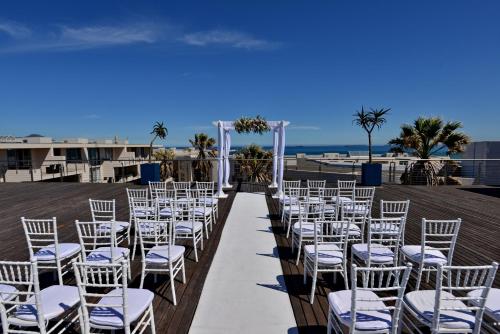 a row of white chairs and a aisle at a wedding at Lagoon Beach Hotel & Spa in Cape Town