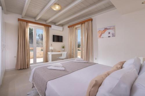 a bedroom with a large white bed and a window at Villa Niragia with Magnificent view in Astérion