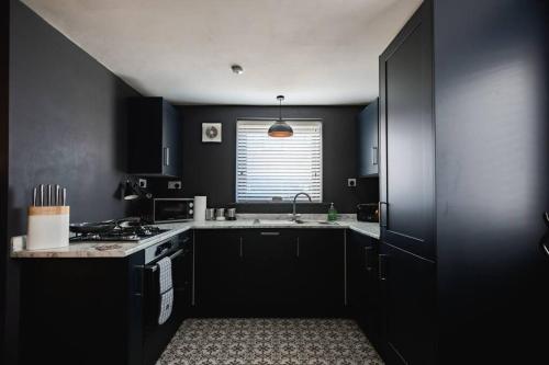 a black kitchen with a stove and a window at Hullidays》Old Town Luxury Cavern in Hull