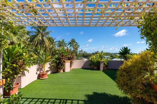a patio with plants and a pergola at Blue Wave Hotel Maldives in Kudahuvadhoo