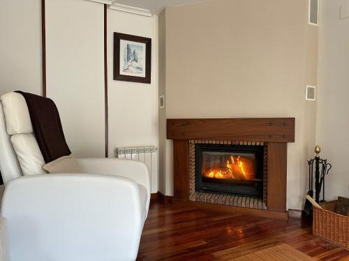 a living room with a fireplace and a white chair at Paseo Tenorio, remanso de paz con PISCINA in Ezcaray